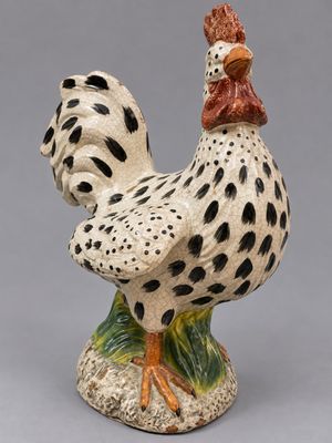 une figurine en céramique représentant un coq posé sur un rocher