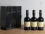 trois bouteilles de vin posées sur une table en bois, à côté d'une boîte
