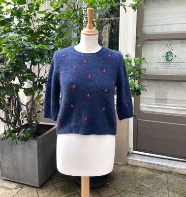 blue sweater with red cherries on it on a mannequin