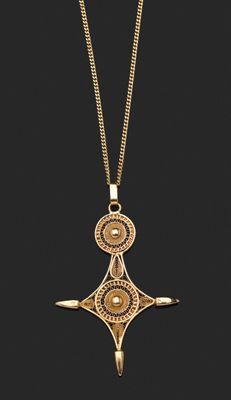 un collier en or avec une croix suspendue à une chaîne, sur fond noir