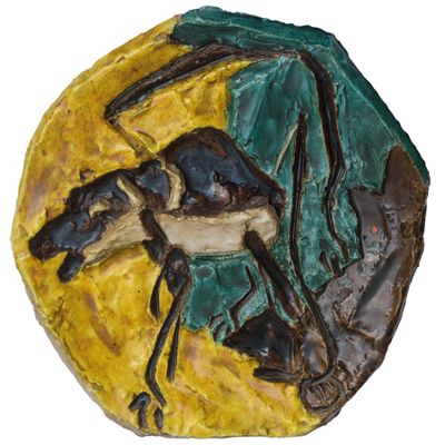 une photo d'une sculpture en céramique représentant un cheval, posée sur une assiette jaune et verte