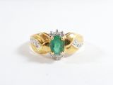 gros plan d'une bague en or avec une pierre verte et des diamants