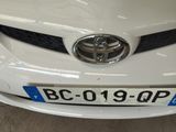 a white toyota car with a blue license plate on it