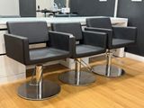 four black chairs sitting in front of a counter in a salon