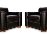 une paire de fauteuils club en cuir noir avec des pieds en bois