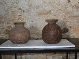 deux vases posés sur une table devant un mur de briques