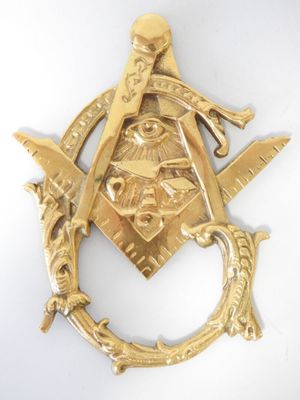 broche représentant une équerre et un compas maçonniques dorés sur fond blanc