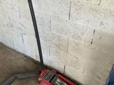 an image of a garage with a blue car and a red jack
