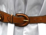 a woman wearing a white dress and a brown belt