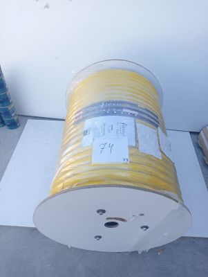 a roll of yellow wire on the ground next to a wall