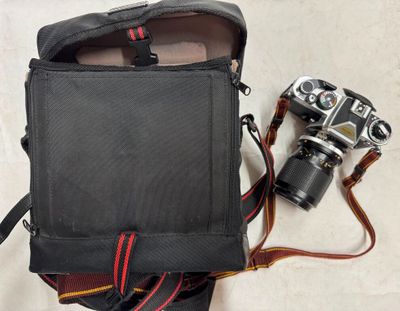a black bag with a camera and a camera strap