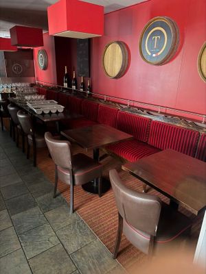 tables and chairs in a restaurant with red walls and a clock on the wall