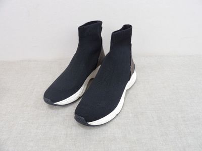 une paire de baskets noires à semelles blanches posées sur une surface grise