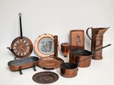many different types of copper pots and pans on the table