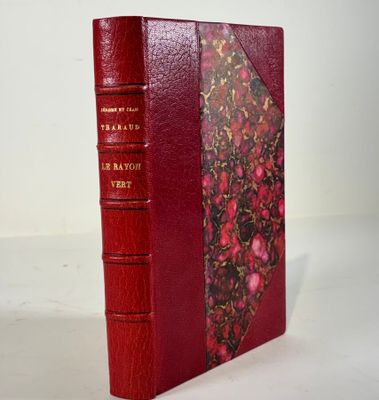 un vieux livre à la couverture rouge posé sur une table blanche