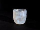 a frosted glass cup sitting on a black surface