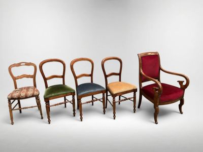 four chairs in different colors are lined up against a white wall