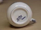a close up of a white cup with blue writing on it