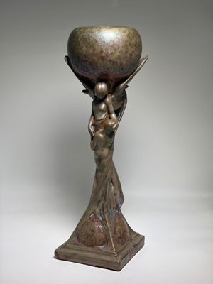bronze statue of a woman holding a bowl on her head