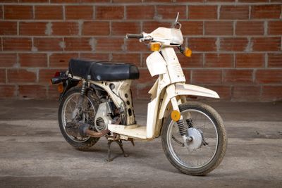 a white motor bike parked in front of a brick wall