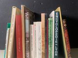 Plusieurs livres sont alignés sur une étagère devant un mur noir