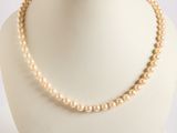 collier de perles présenté sur un mannequin devant un fond blanc