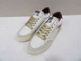 des baskets blanches ornées de lacets dorés, posées sur une surface blanche