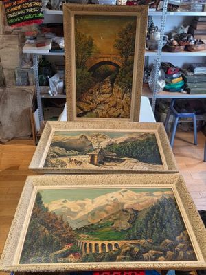 Deux tableaux représentant des montagnes et un pont sont exposés dans une boutique.