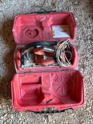une mallette à outils rouge posée par terre, contenant des outils