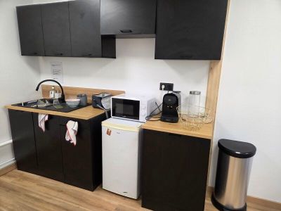 a small kitchen with black cabinets and a white refrigerator