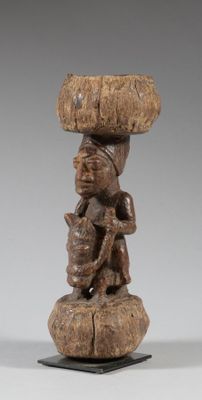 une statue en bois représentant une femme portant un panier sur la tête