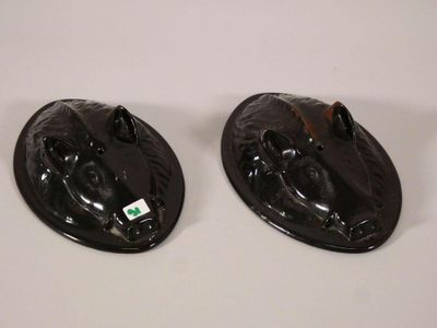 deux têtes d'animaux en céramique noire posées sur une table blanche