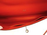 a close up of a person holding a red purse on a white surface