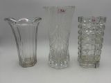 three glass vases are lined up on a white surface