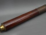 an old wooden telescope with brass fittings on a grey background