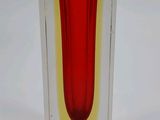 a glass vase with a red and yellow design on it