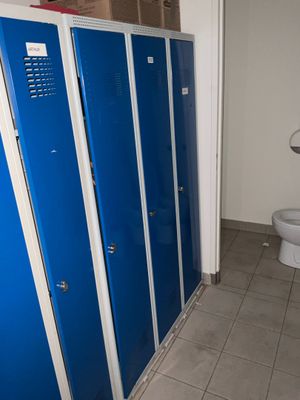 trois casiers bleus dans une salle de bains avec des toilettes dans un coin