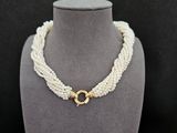 un collier de perles blanches muni d'un fermoir en or, posé sur un mannequin