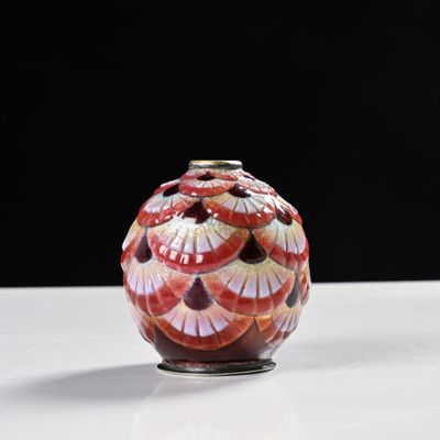 un vase rouge et blanc posé sur une table blanche
