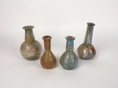 Trois vases sont posés sur une surface blanche ; l'un est bleu et l'autre est vert.