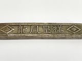 a silver bar with chinese writing on it sitting on a white surface