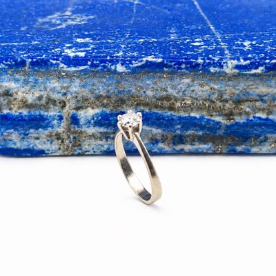 an image of a diamond ring sitting on top of a piece of blue marble