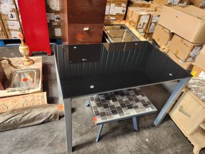 a black table with a glass top in a warehouse