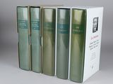 four books in a row sitting on top of a white table
