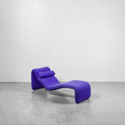 une chaise longue violette dans une pièce blanche