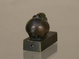 sculpture of a frog sitting on top of a small metal object