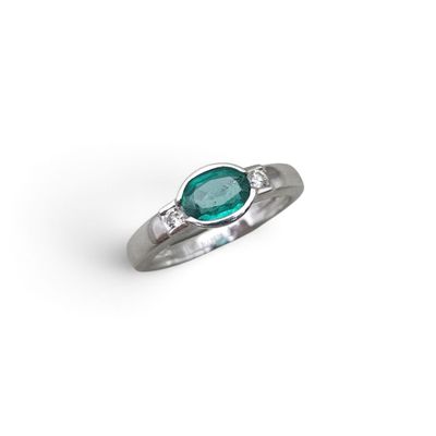 a close up of a ring on a white surface with a green stone