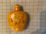 une bouteille jaune ornée d'une image, posée sur une table