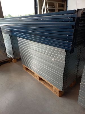 plusieurs piles de tôles d'acier empilées sur des palettes dans un entrepôt