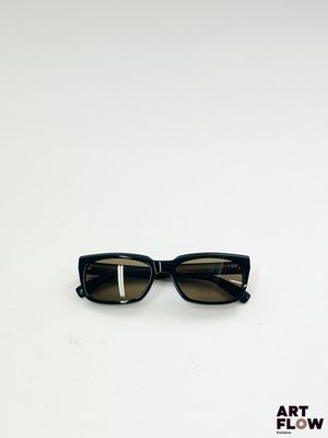 une image représentant une paire de lunettes de soleil noires posées sur une surface blanche